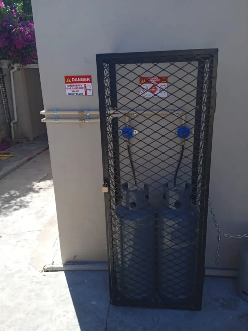 Two LPG cylinders in a lockable steel cage with warning signs
