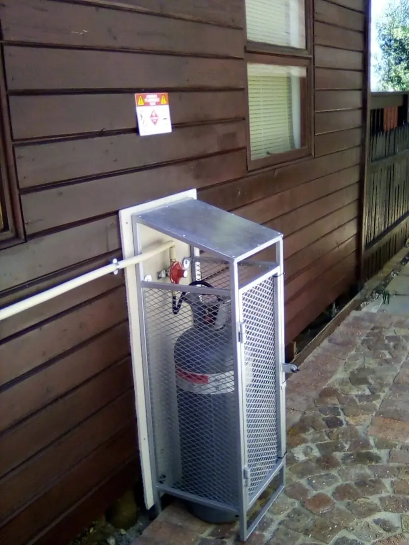 A gas cylinder in a cage against a timber house