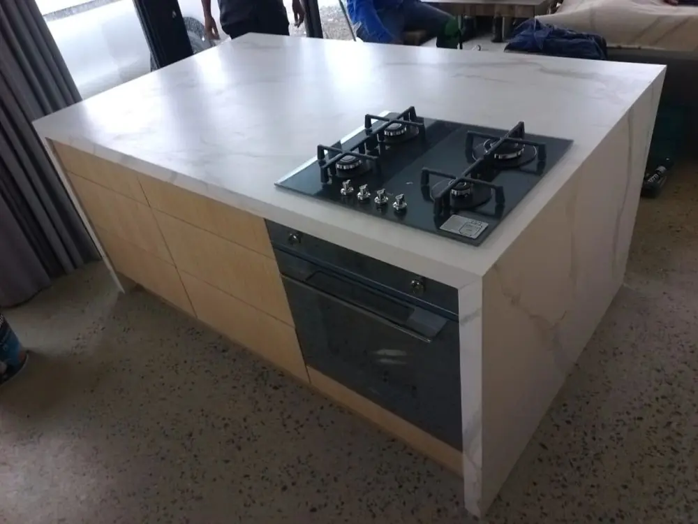 A black glass gas hob built into a kitchen island