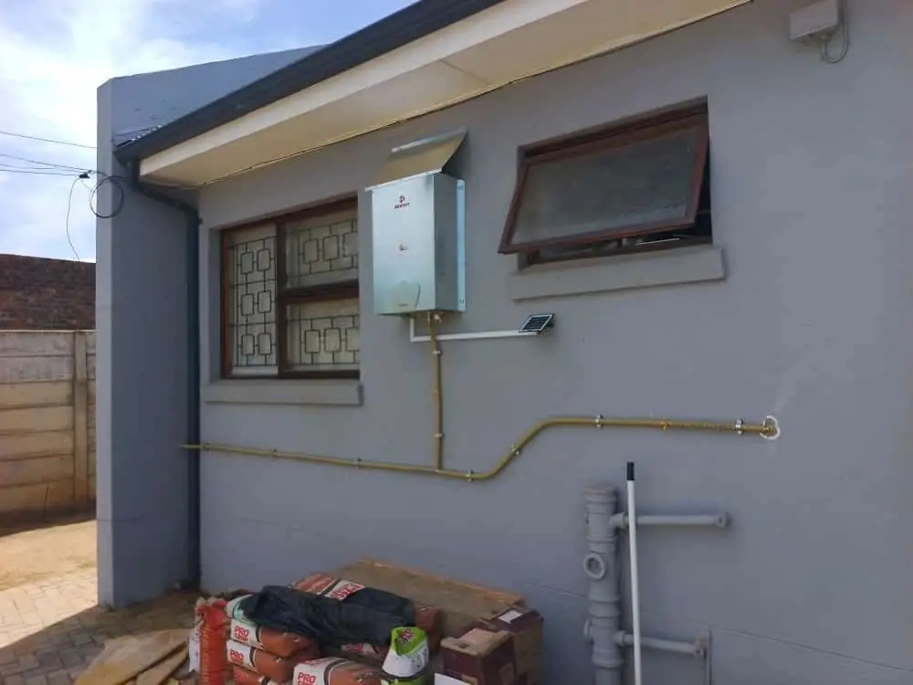 Gas piping run neatly along the outside wall of a house to a geyser