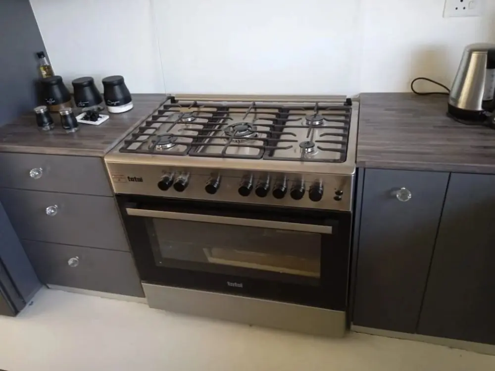 A gas stove fitted between grey kitchen cupboards