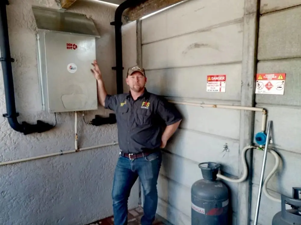 Wayne Taylor next to a Dewhot gas geyser he installed
